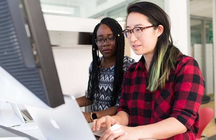 Two colleagues collaborating on marketing designs at a computer