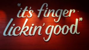 Image of a red wall with the KFC slogan "it's finger lickin' good"